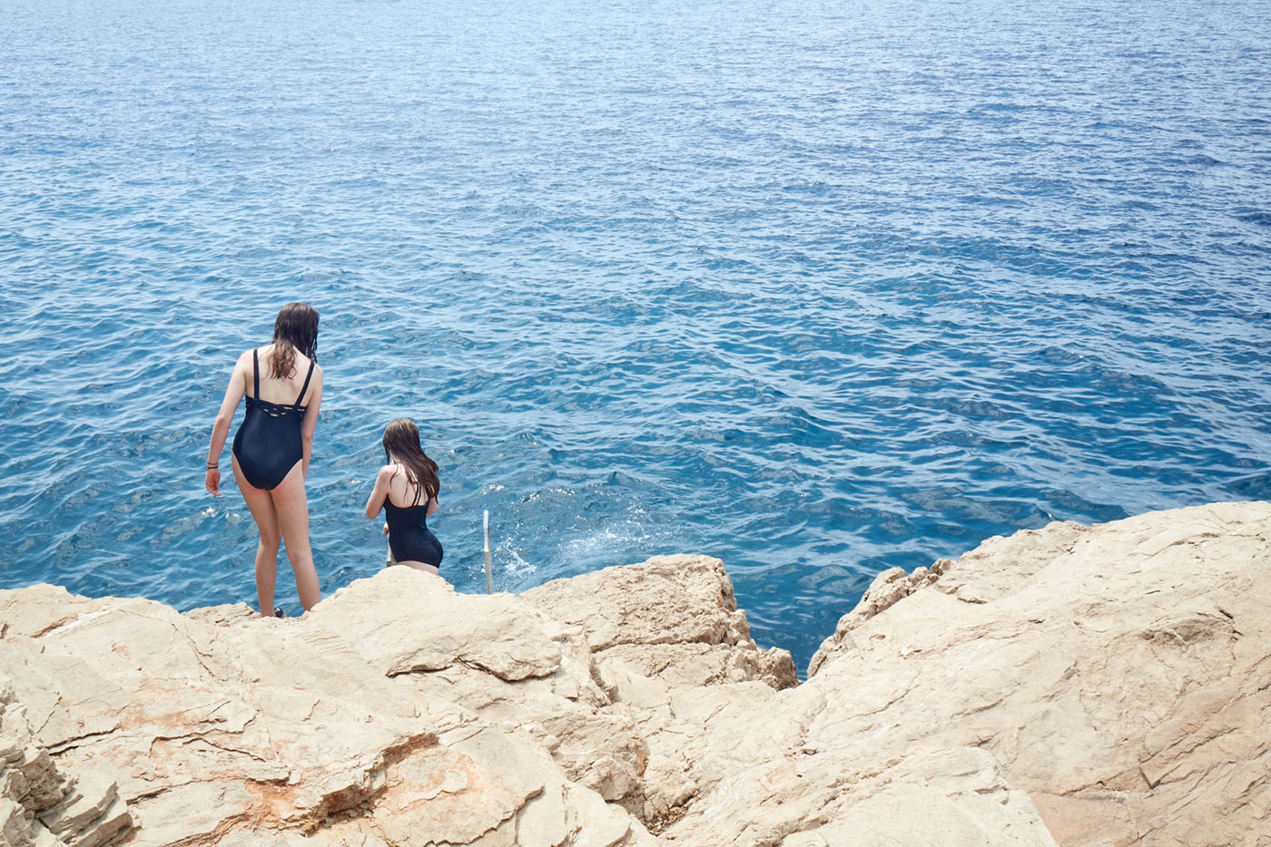 Two girls ready to jump in the sea
